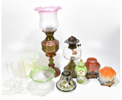 An early 20th century oil lamp with cranberry and frosted glass shade above the clear glass reservoir and gilt metal base sec