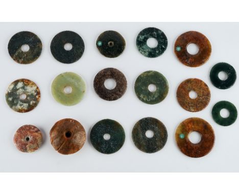 A group of sixteen Chinese archaistic jade bi discs and a weaver's weightof various sizes and colours, sizes 4.5cm to 6.5cm d