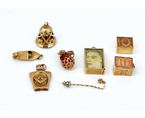 Seven mostly gold pendants and charms and a stick pin (8)A 9ct gold charm designed as a hinged bell, opening to reveal a wedd