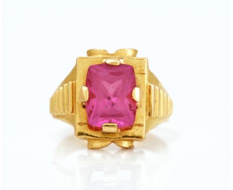 A gold and synthetic ruby single stone ringClaw set with a curved rectangular cut synthetic ruby between ridged shoulders, un