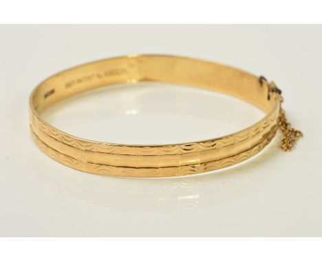 A 9CT GOLD BANGLE, of faceted design with diamond cut swag detail to the edges, with 9ct hallmark for London, inner diameter 