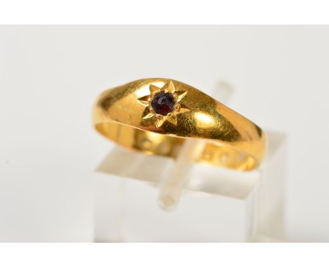 A LATE VICTORIAN 22CT GOLD RING, designed with a central circular red gem assessed as a garnet within a star setting, with 22