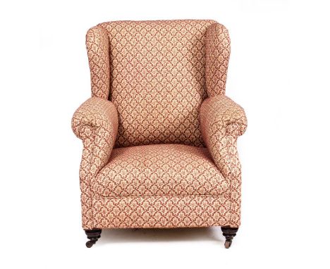 A VICTORIAN OR EDWARDIAN UPHOLSTERED WING BACK ARMCHAIR with turned front legs and ceramic casters, 78cm wide x 81cm deep x 9