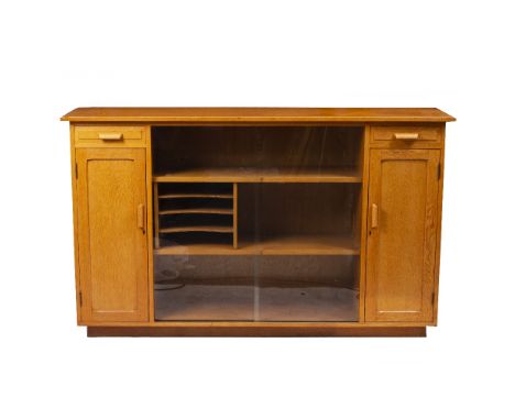 A MID 20TH CENTURY HAND MADE LIGHT OAK SIDE CABINET with cupboards and slides behind two sliding glazed doors flanked by cupb