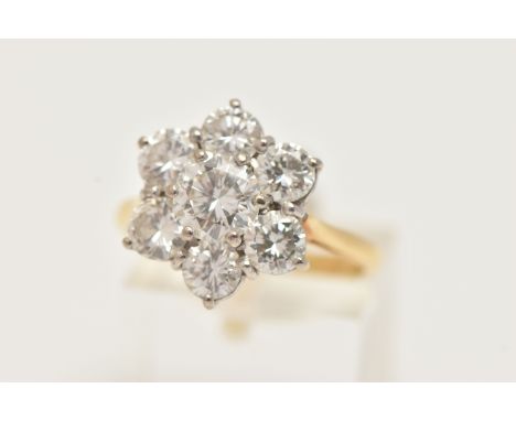 AN 18CT WHITE AND YELLOW GOLD DIAMOND CLUSTER RING, set with a principal round brilliant cut diamond, measuring approximately