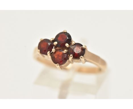 A 9CT GOLD GARNET RING, set with four circular cut garnets, each in a four claw setting, to a polished band, hallmarked 9ct L