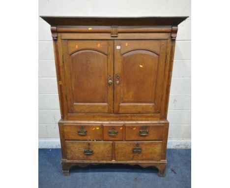 A GEORGIAN OAK TWO DOOR CUPBOARD, the fielded panel doors enclosing a single shelf, atop a base with five drawers, on high br