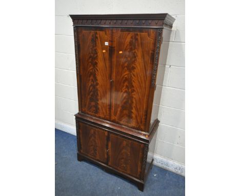 A MAHOGANY FOUR DOOR DRINKS CABINET, enclosing three glass shelves, cutting slide, atop a base with double cupboard doors, wi