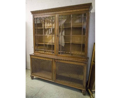 BOOKCASE, George IV mahogany with two glazed doors enclosing adjustable shelves above two grille fronted doors on short turne