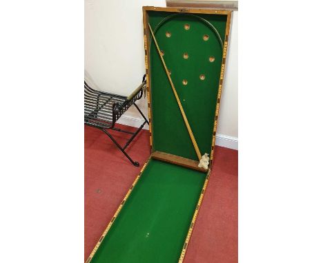 An early 20th century mahogany fold-over table bagatelle board, having baize lined interior (one cue and sundry balls), 122 x