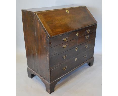 A George III Oak Bureau, the moulded fall front enclosing a fitted interior with sunken well above two short and two long dra
