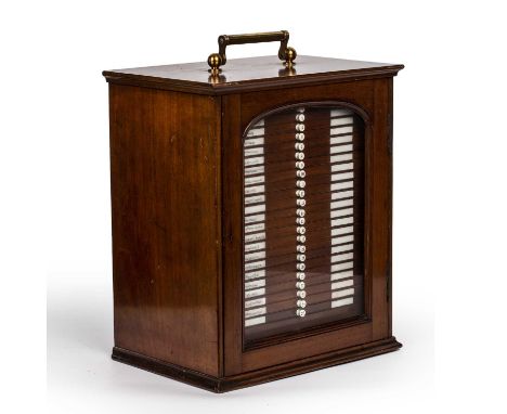 A Victorian mahogany microscope specimen slide case with a lacquered brass carrying handle, a glazed door and twenty six draw