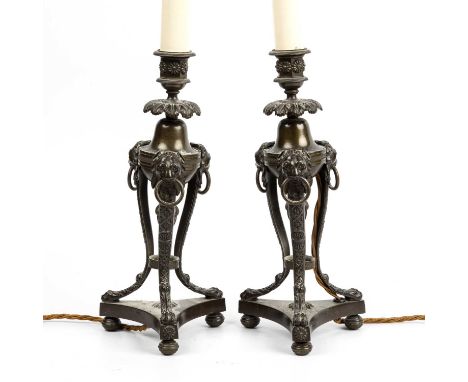 A pair of Regency bronze candlesticks with lion ring masks and triform bases, 13cm wide, 31cm highconverted to electric.