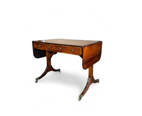 A Regency rosewood sofa table
The hinged rounded rectangular top above two frieze drawers, on standard end supports and reede