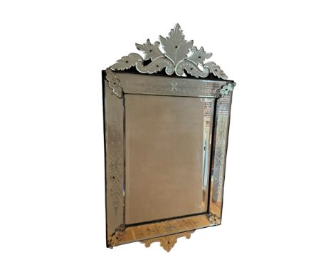 A vintage Venetian style etched wall mirror
The rectangular plate with outer plates surmounted by a scrolling leaf cresting, 