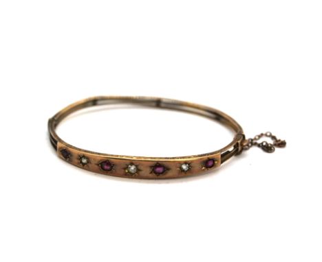 An Edwardian 9ct rose gold bangle set with old cut diamonds and rubies, L. 6cm.&nbsp;Weight - 7.3g.