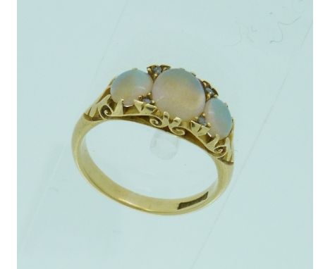 A graduated three stone opal Ring, with diamond points between the centre stone, mounted in 18ct yellow gold, Size L.