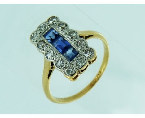 An attractive c.1920 Dress Ring, the oblong front set with three millegrain set calibre sapphires, and in a shaped surround w