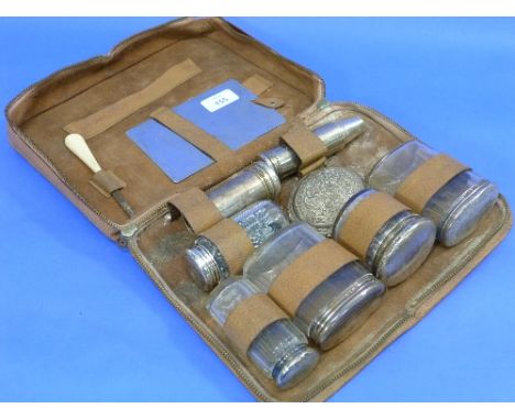 A four-piece silver-mounted cut glass travelling Vanity Set, incomplete, in fitted leather case, and three silver-mounted cut