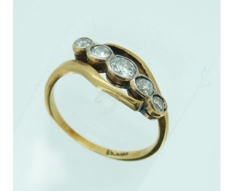 A graduated five stone diamond Ring, with rubbed over settings, set on the cross in an 18ct yellow gold mount, c.0.85ct Size 