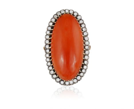 A CORAL AND DIAMOND COCKTAIL RING, CIRCA 1950Composed of a large elongated oval-shaped corallium rubrum cabochon, within a su