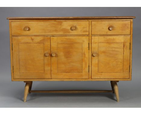 An Ercol light elm small sideboard fitted two frieze drawers above cupboards enclosed by three panel doors, &amp; on short tu