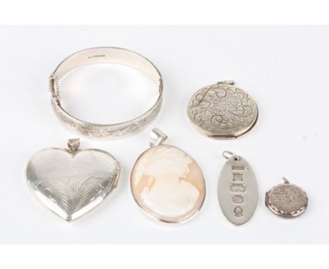 A collection of silver items
including an oval silver ingot, a stiff bangle, a heart shaped locket pendant, a cameo pendant a