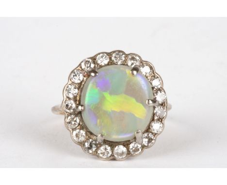 An opal and diamond cluster ring
set with large opal surrounded by nineteen small diamonds, in an unmarked yellow metal mount