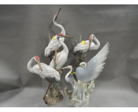 Three Lladro figures of storks in the bulrushes together with a Nao of figure of herons A/F 