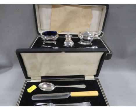 A boxed hallmarked silver three piece cruet set together with two matched spoons and a cased christening set with silver fork