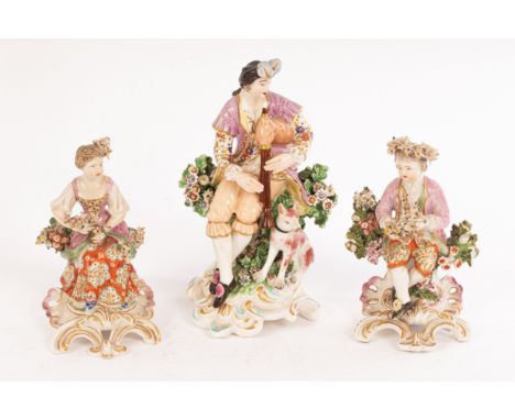 A Derby figure of a seated shepherd playing the bagpipes, 17cm high and a pair of smaller figures with flower garlands, 13cm 