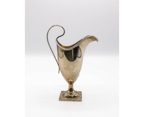 A silver cream jug, Henry Williamson Ltd., Birmingham 1923, of helmet-shape with a ribbed scroll handle on a square pedestal 