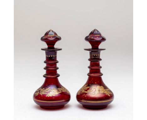 A pair of ruby glass liqueur bottles and stoppers, circa 1900, with triple-ring necks, enamelled with fruiting vines, 15cm hi