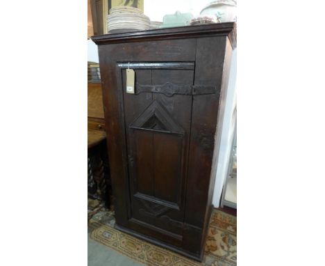 A 17th century oak hall cupboard, with carved lozenge panel door having cast iron hinges, raised on stepped base, H.134 W.71 