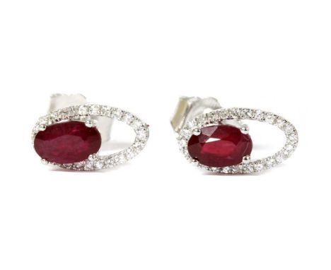 A pair of white gold ruby and diamond halo stud earrings, an oval mixed cut ruby, approximately 5 x 3mm, claw set to openwork