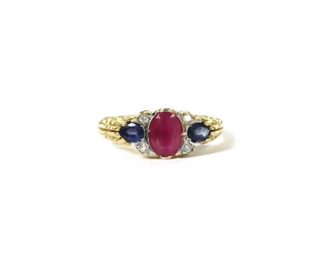 An 18ct gold ruby, sapphire and diamond ring, an oval mixed cut ruby with a pear mixed cut sapphire at each side, and brillia