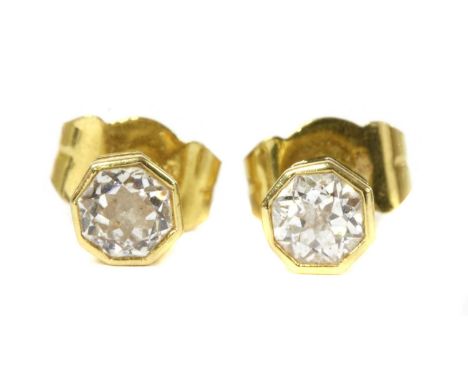 A pair of 18ct gold single stone diamond stud earrings, an octagonal modified brilliant cut diamond, rub set, to post and but