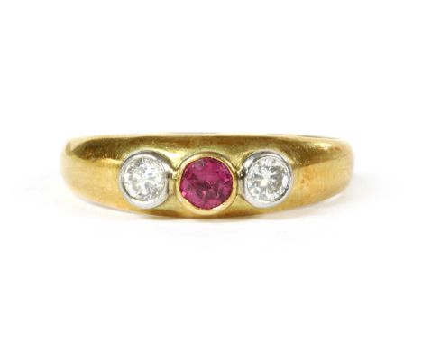 An 18ct gold ruby and diamond three stone ring, a circular mixed cut ruby, rub set, with a brilliant cut diamond at each side