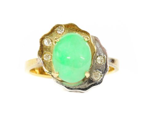 A two colour gold jade and diamond ring, an oval cabochon jadeite jade, claw set to yellow and white gold head, spitch set wi