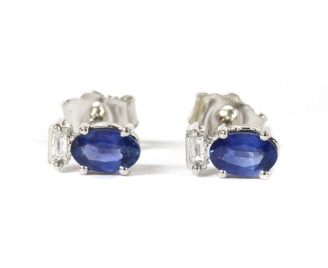 A pair of white gold sapphire and diamond stud earrings, an oval mixed cut sapphire, approximately 5 x 3mm, surmounted with a