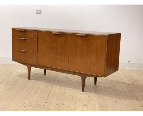 Mcintosh, A mid century teak sideboard, with twin doors enclosing a shelf, flanked by three drawers, raised on turned tapered