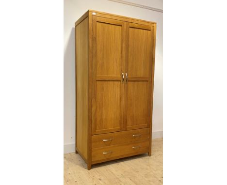 A contemporary light oak wardrobe, the double doors with hanging rail behind, over two long drawers, on tapered supports, H19