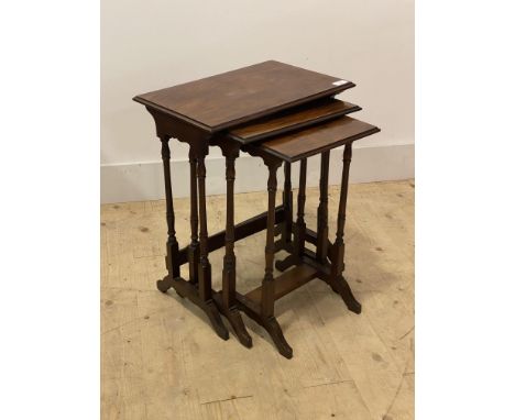 An early 20th century walnut nest of three tables, raised on ring turned and sledge supports, H57cm, W44cm, D30cm