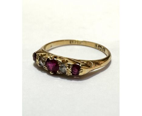 An 18ct gold three stone ruby and and two stone diamond ring, 0.2ct, flanked by a mixed cut stone and a ruby to each shoulder