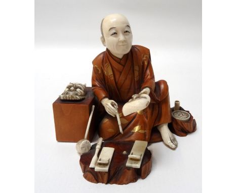 CARVED JAPANESE IVORY AND BOXWOOD OKIMINOof a Noh mask maker, seated with his masks and tools around him, next to a detailed 