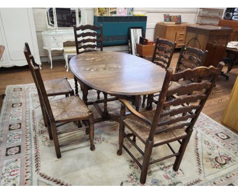 An oak oval drop leaf dining table with barley twist legs and six matching dining chairs, ladder back with rattan seats. Two 