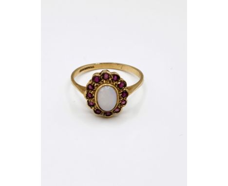 A 9ct yellow gold, ruby and opal ring, set with an oval cabochon opal, the round-cut rubies set in a scalloped border, size P