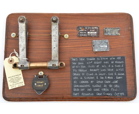 A small display of German aircraft parts, comprising a pair of rockers from the engine, a hinged switch or button cover with 