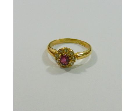 An early 20th century 18 carat gold ruby and diamond circular cluster ring, the oval mixed cut ruby within nine stone old-cut