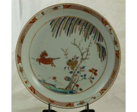 A Kangxi porcelain famillè vert dish decorated with a horse and a willow tree, 23cm diameter CONDITION REPORT: Three hairline